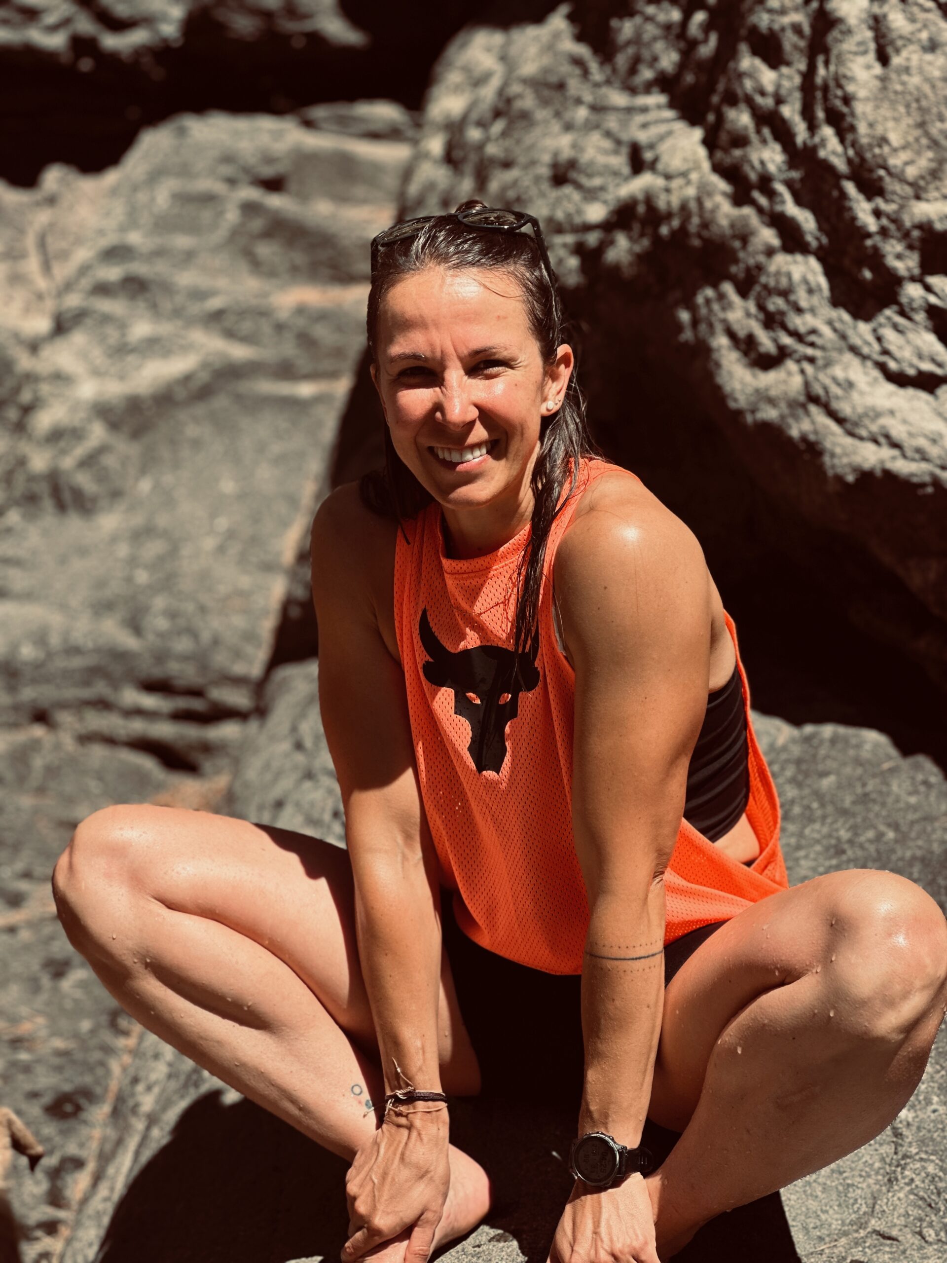 Anja im Sommer in sportlichem Outfit sitzend auf einem Felsen